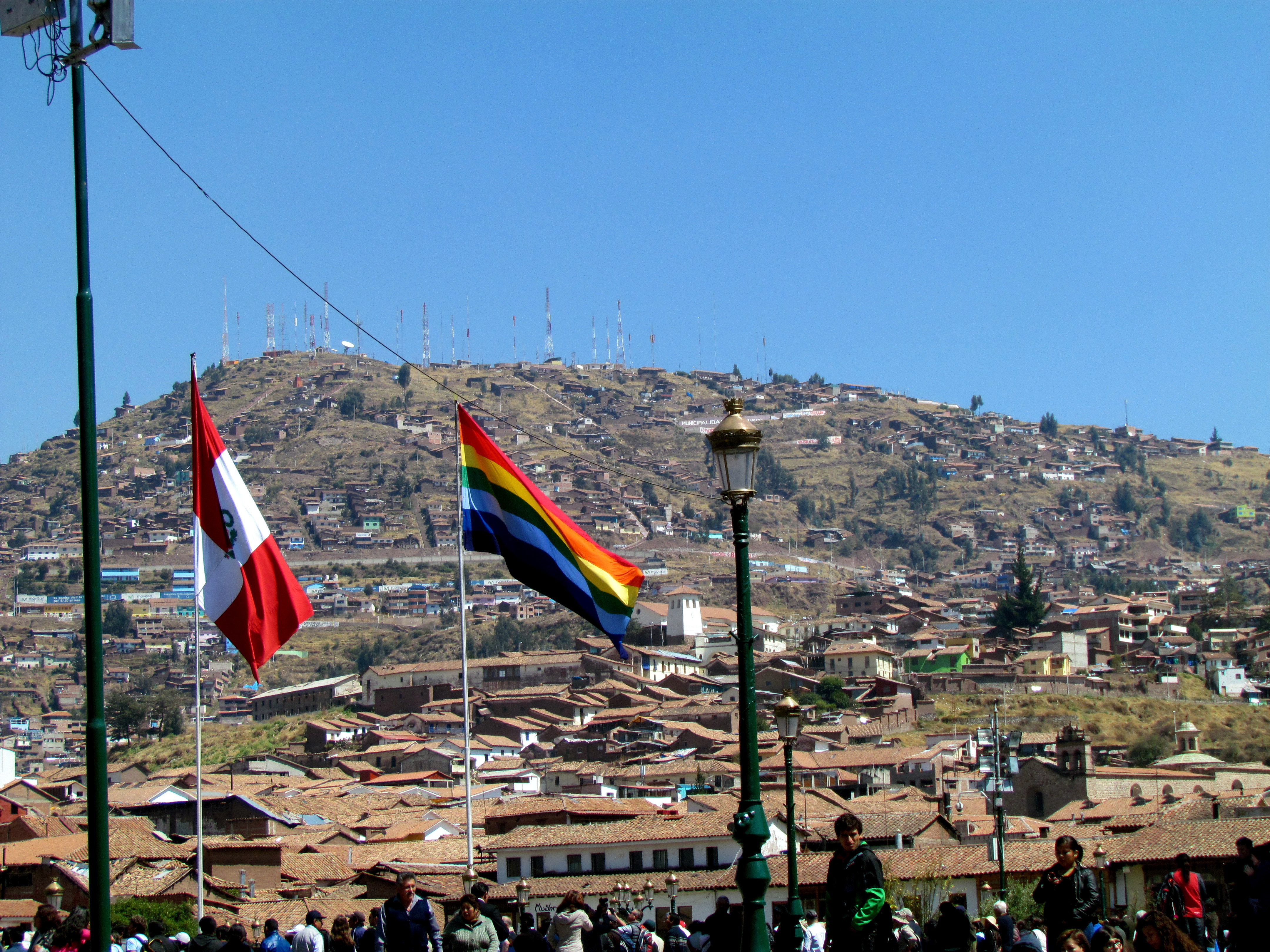 Cusco rooftops and hills seen beside the Peruvian and Cusco flags