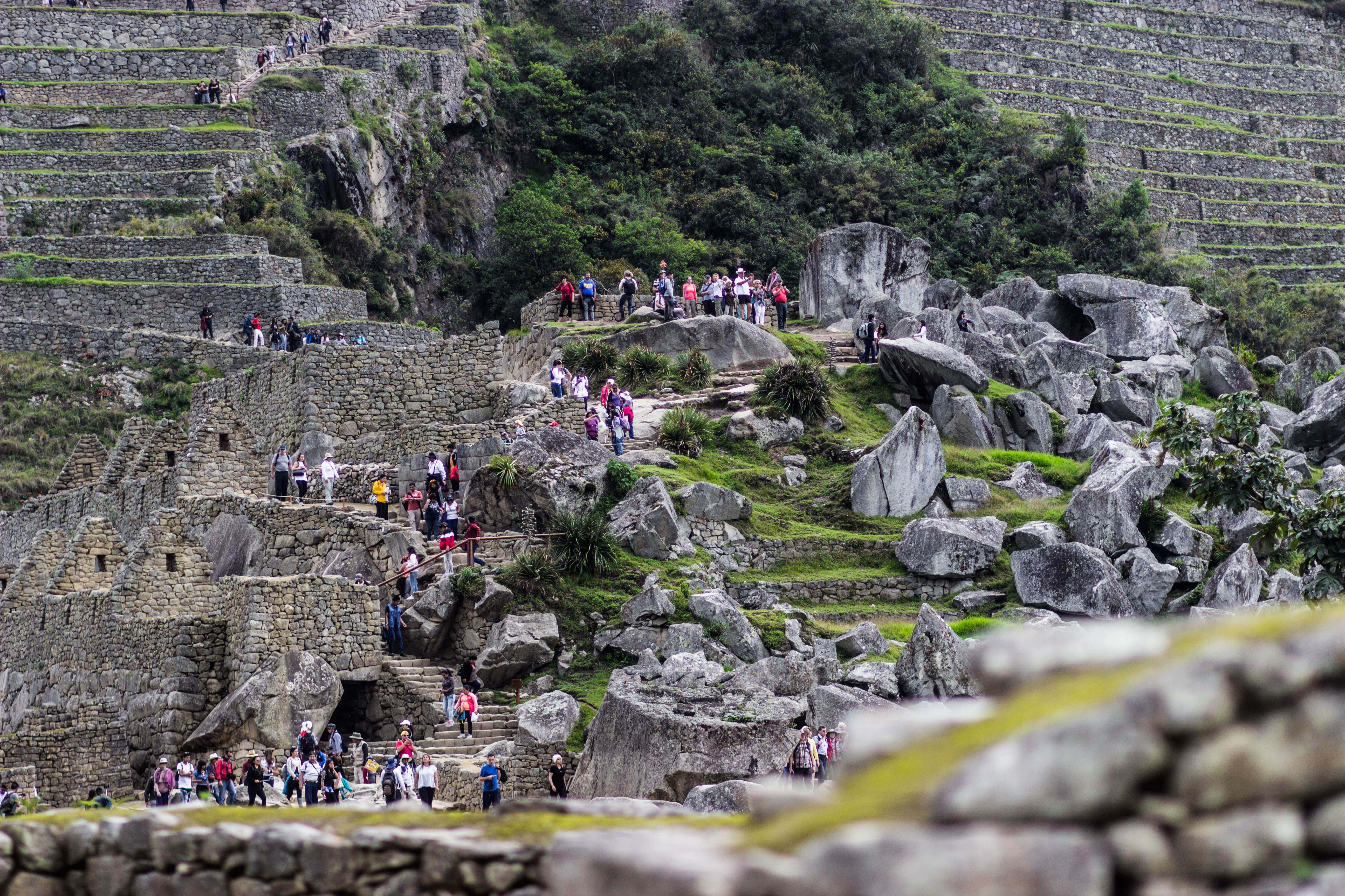 Travelers crossing the lower terraces and stone paths at Machu Picchu