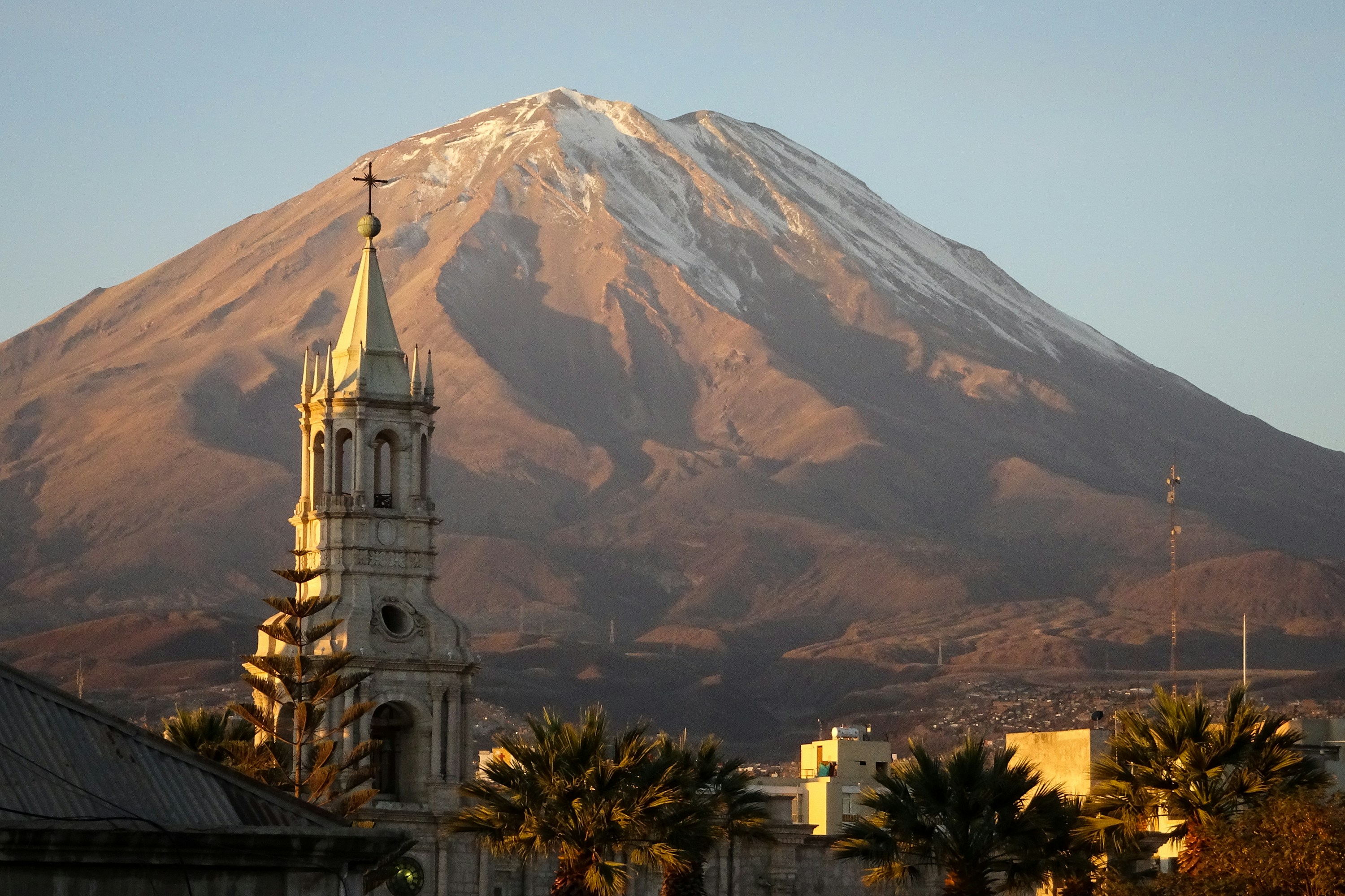 A church bell tower and Arequipa rooftops beneath El Misti volcano