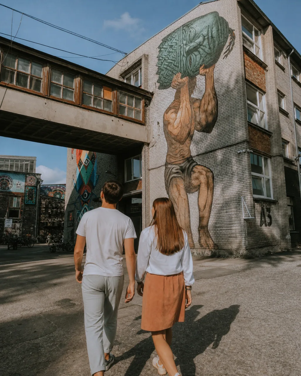 Travelers entering Telliskivi's mural-covered railway workshops