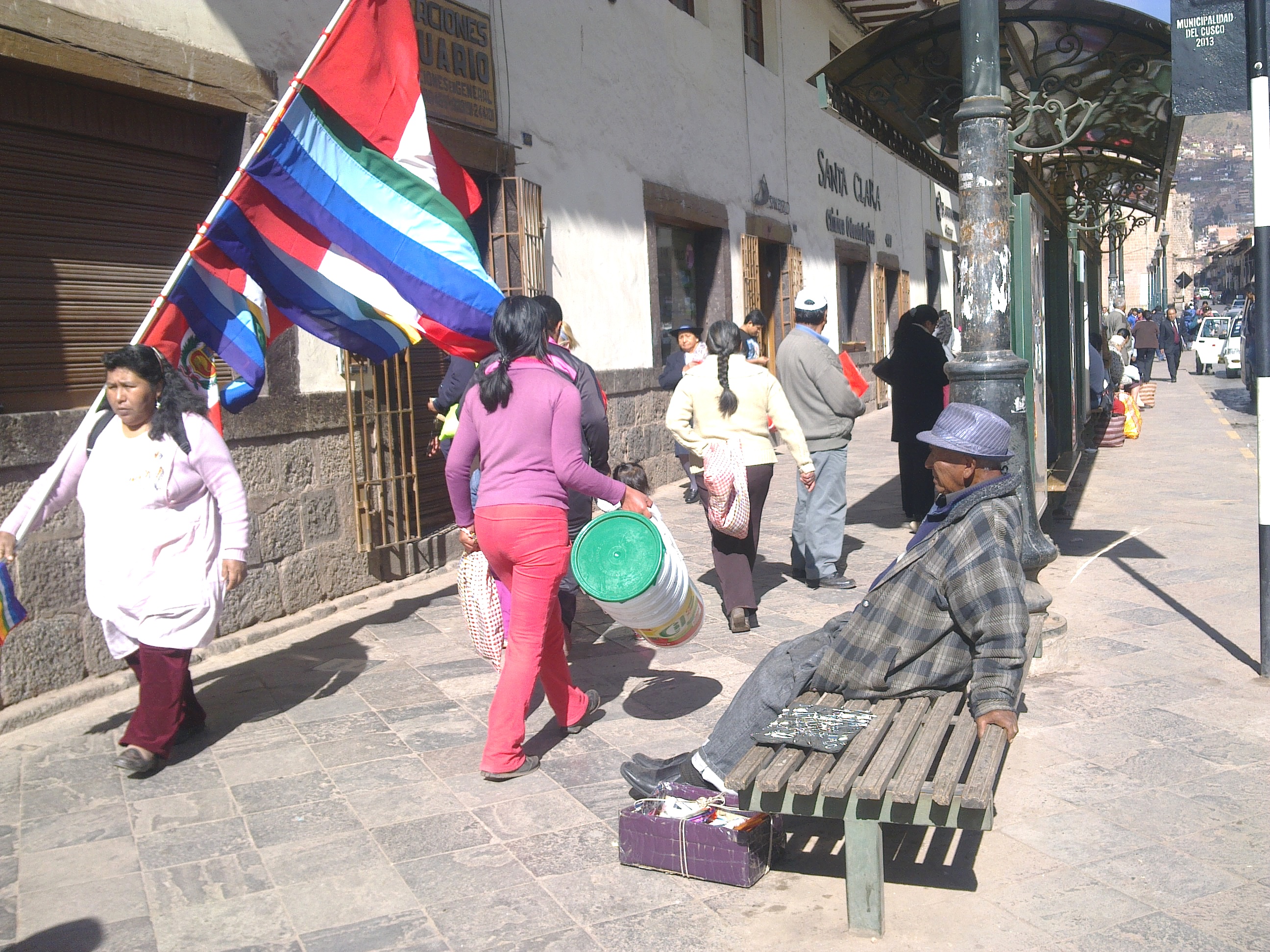 People walking past stone buildings and street vendors on Calle Santa Clara in Cusco